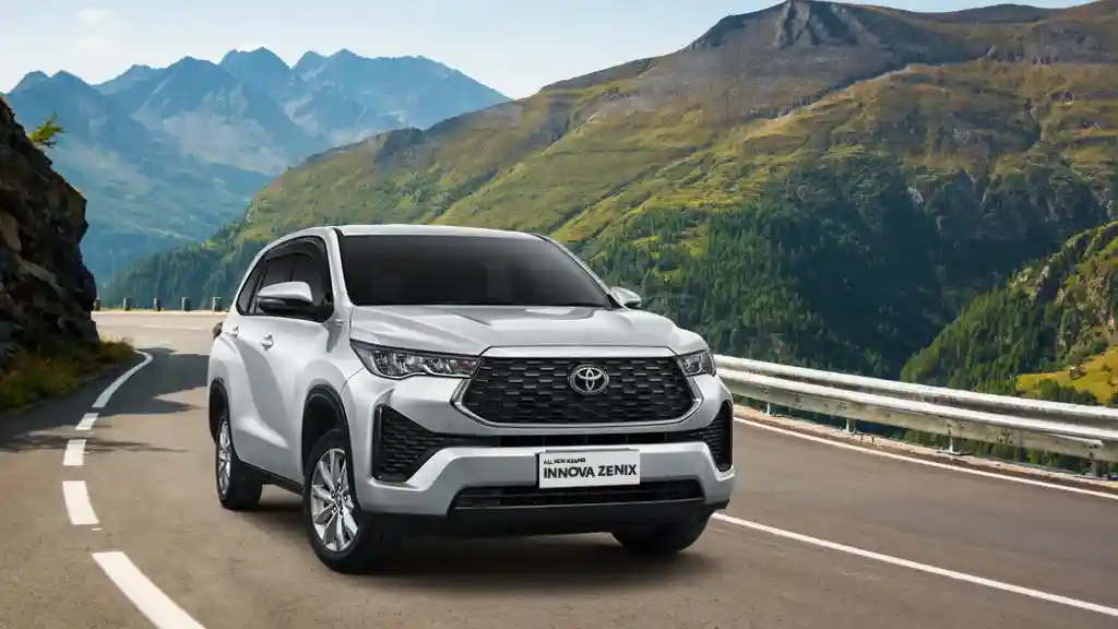 Toyota Innova Zenix melintasi jalan berkelok dengan latar perbukitan hijau